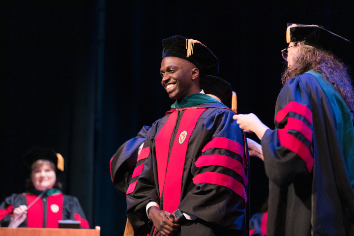 A graduate smiling big onstage at MD graduation