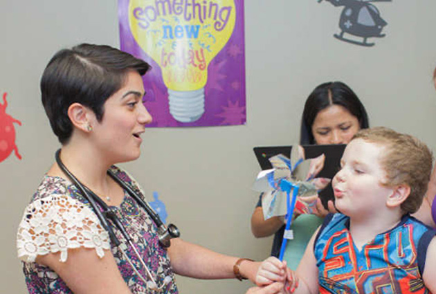 A doctor engaging a child with a pinwheel in a clinic
