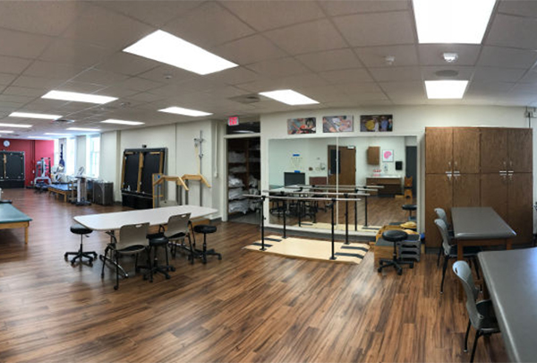 A studio space with physical therapy treatment tables, a mirror and other equipment