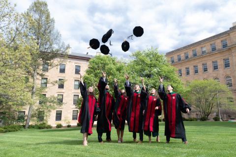 MD graduates throwing their caps in the air in celebration