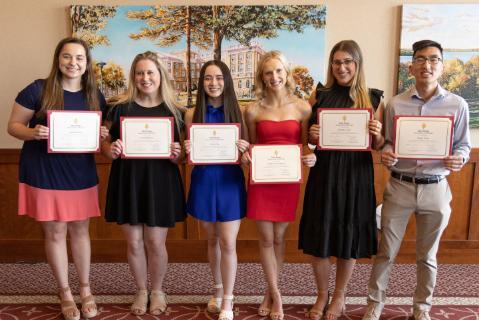 A group of students holding up certificates and smiling for the camera