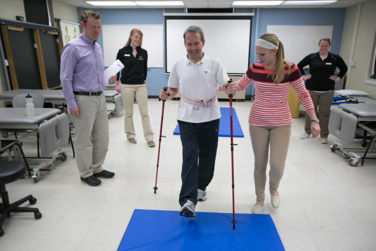 A student helps a patient walk with support