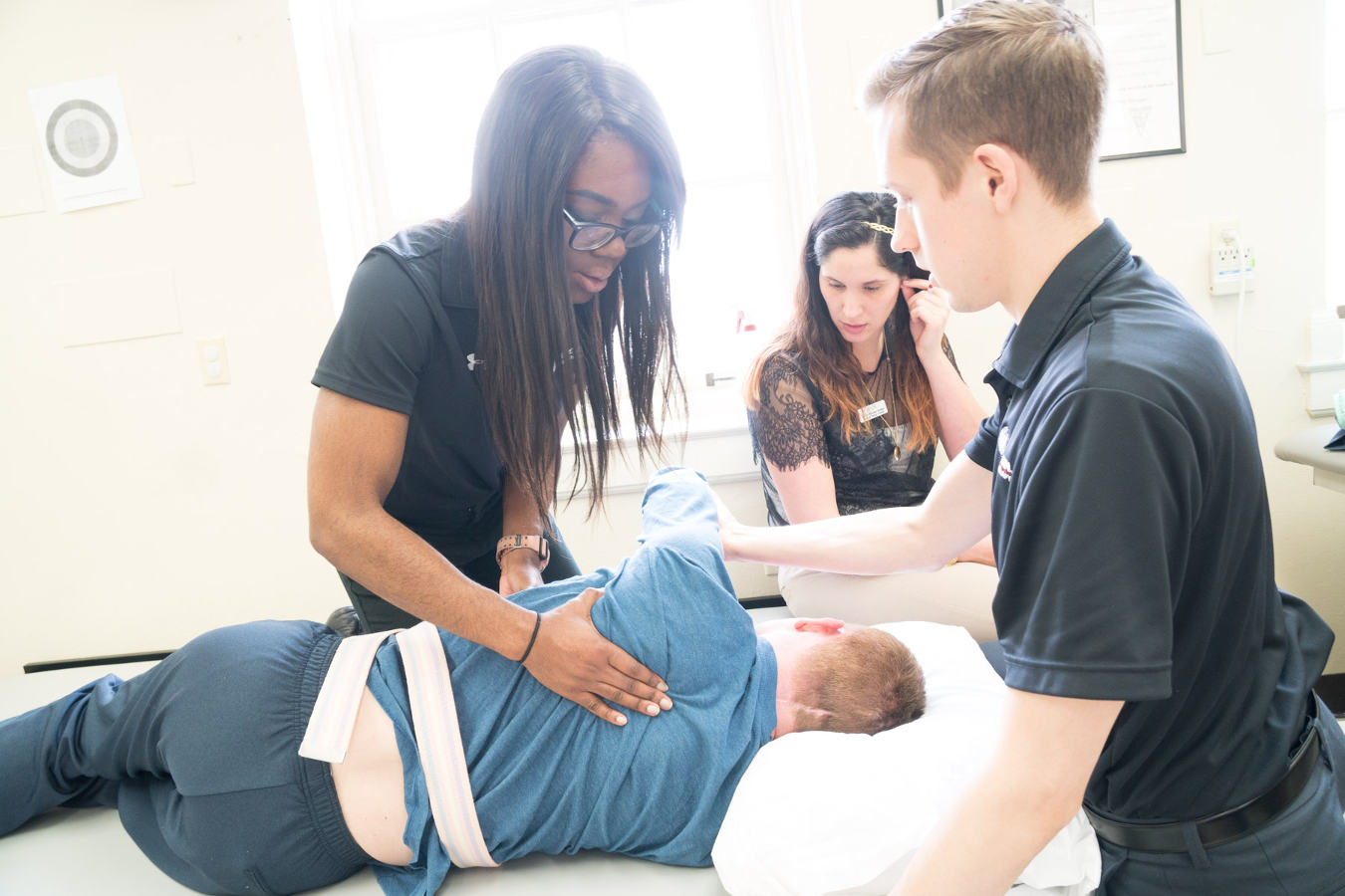 Physical therapy students concentrate on working with a patient