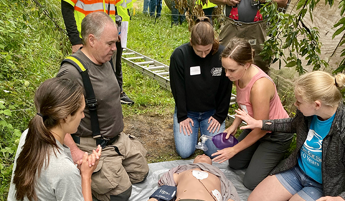 Students kneeling around a training mannequin