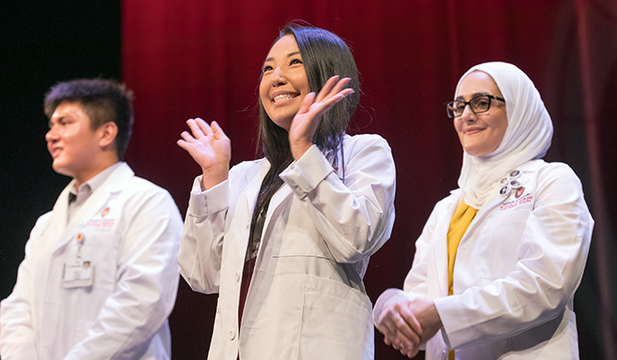 A student smiles and waves at the MD White Coat ceremony in 2023