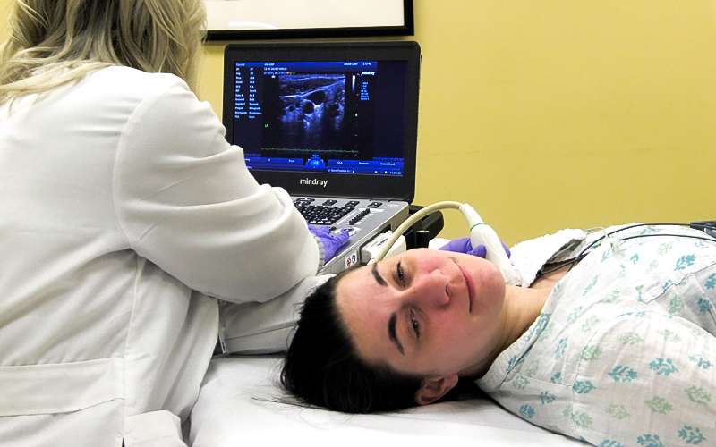 A technician performs and ultrasound on a patient's neck.