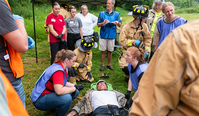 Students and firefighters address medical concerns in a simulated field scenario
