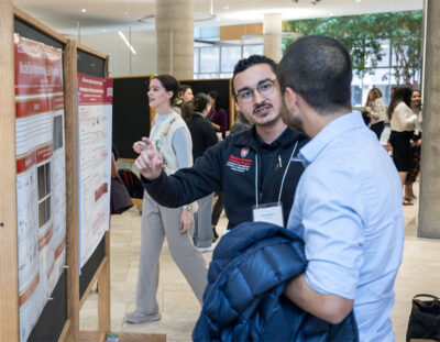A student discusses their research poster