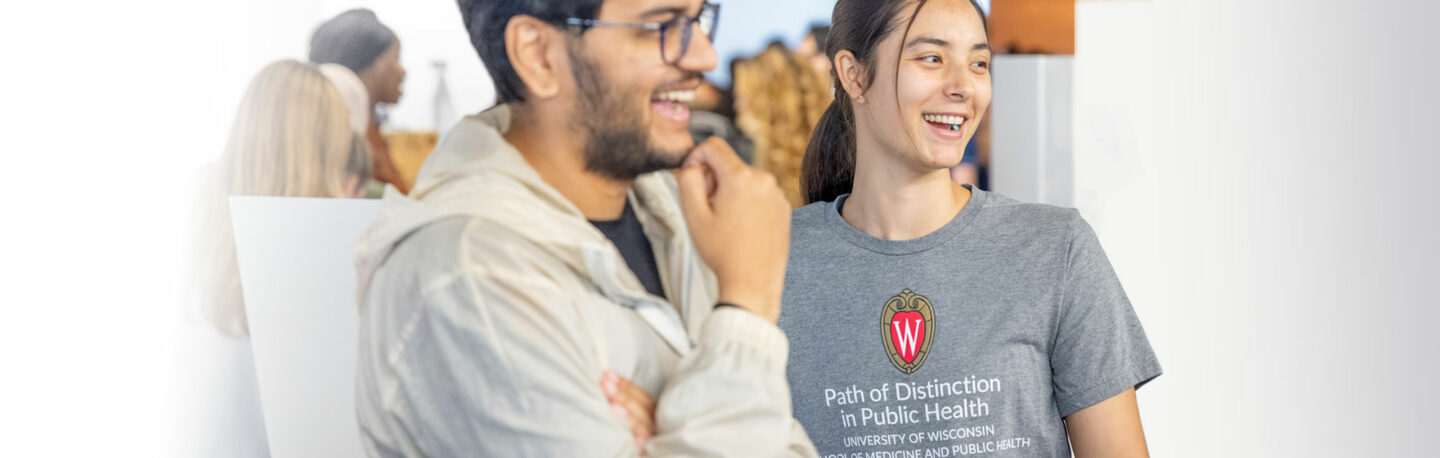 students smiling - one is wearing a UW Path of Distinction in Public Health shirt