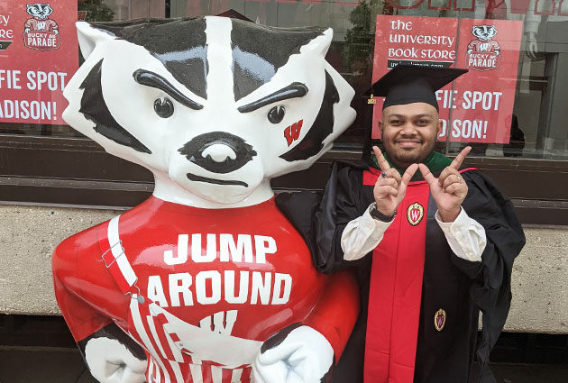 A graduate proudly making a "W" with their fingers to rep UW–Madison