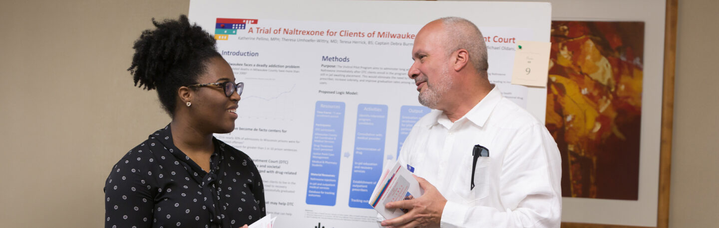 A student and staff member in a happy discussion at a research poster session