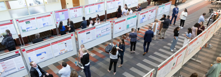 A crowd of students, faculty and community engaging in a poster session
