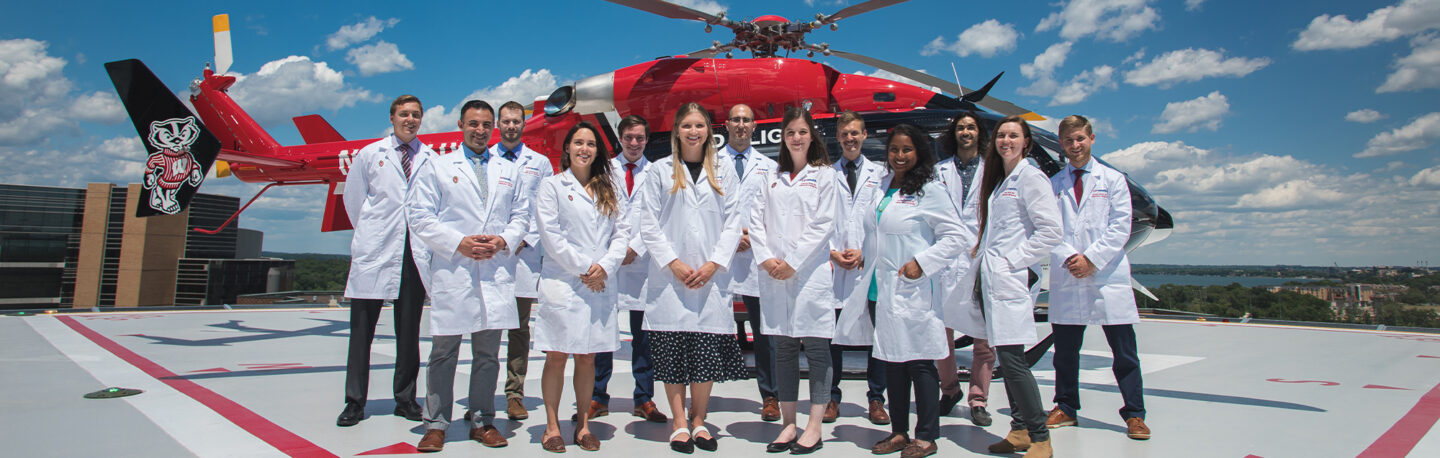 A group of health professions students smiling together in front of an emergency medical helicopter