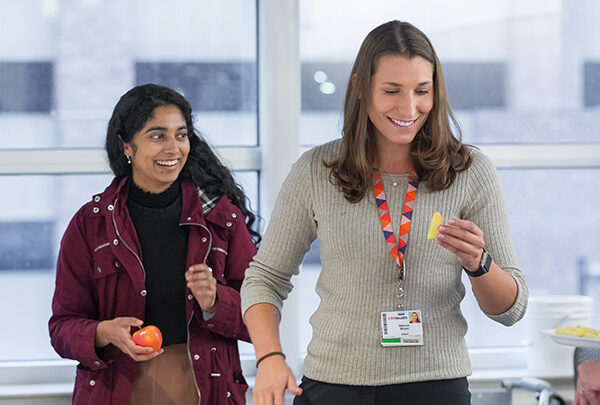 Two students smiling together and eating a healthy snack