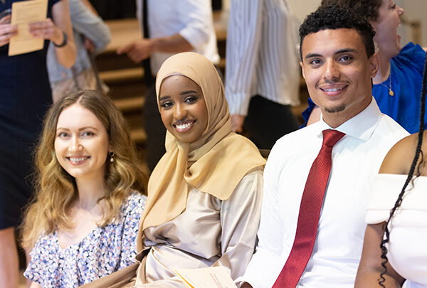 Three students sitting together smile for a picture
