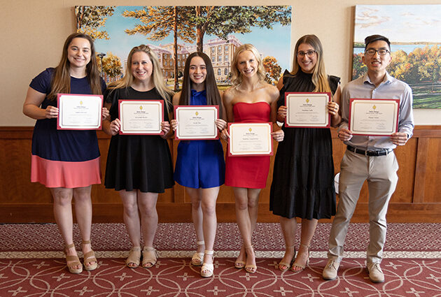 A group of students holding up certificates and smiling for the camera