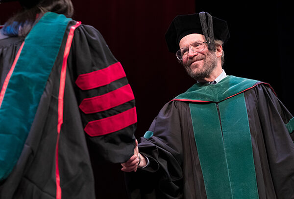 Dean Golden shakes a student's hand at a graduation ceremony