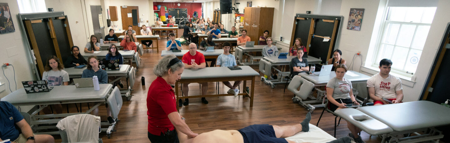Students observing physical therapy practices in a hands-on classroom environment