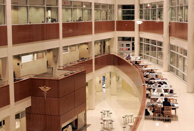 The interior of a multi-floor building with a curved indoor balcony and many places to sit and study