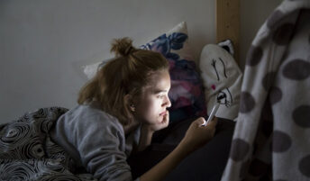 Teen girl staring at her mobile in her room
