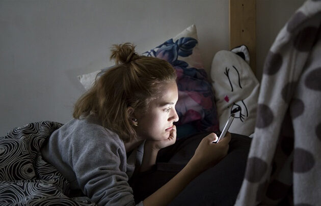 Teen girl staring at her mobile in her room