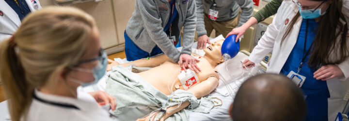 Person performs chest compressions on a mannequin