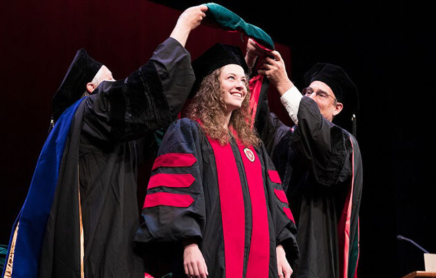 A student excitedly receives their hood at graduation