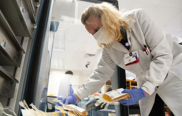 A healthcare worker holding a bag of plasma