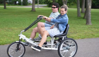 Two people pedaling a three-wheel, two-passenger trike