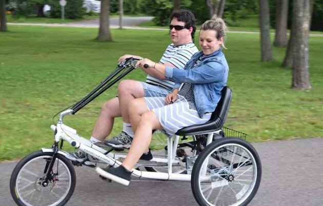 Two people pedaling a three-wheel, two-passenger trike