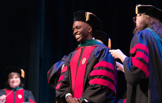 2023 student speaker Nasser Lubega smiling onstage at MD graduation