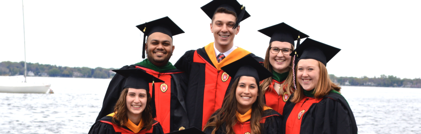 Graduates smiling big and standing lakeside