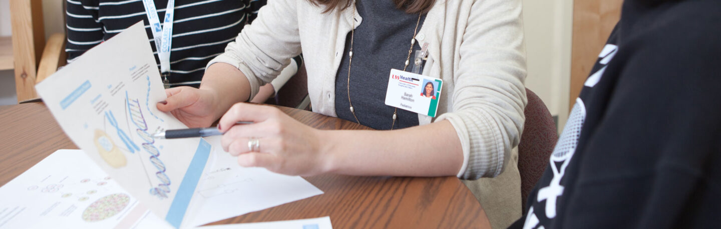 A UW Health employee discussing a double helix image