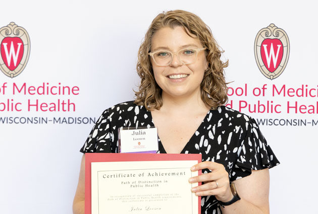 Julia Loosen smiles with her Paths of Distinction in Public Health certificate of achievement