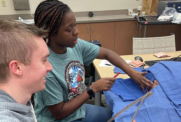 PA students working together on a mannequin in a lab