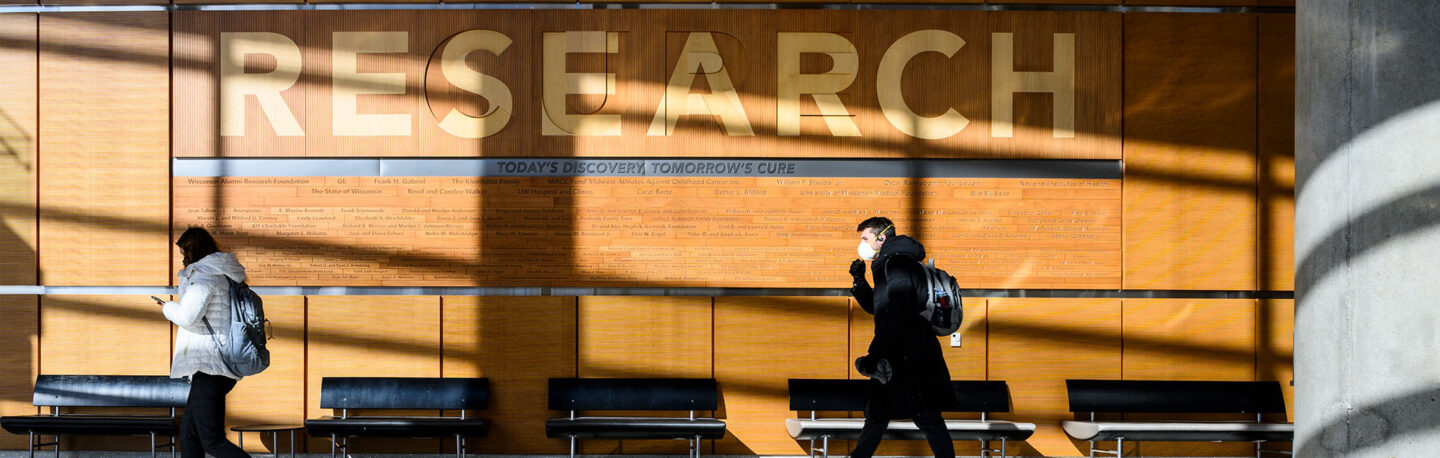 People walking in front of a wall that says RESEARCH