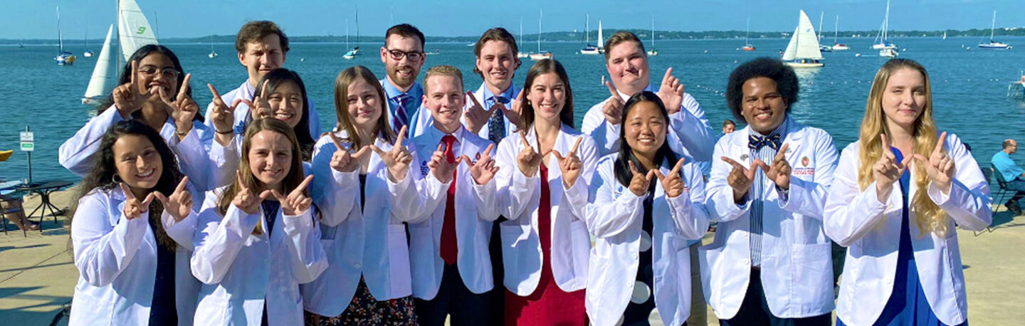 A group of MD-PhD graduate students smiling and showing the UW-Madison "W" symbol