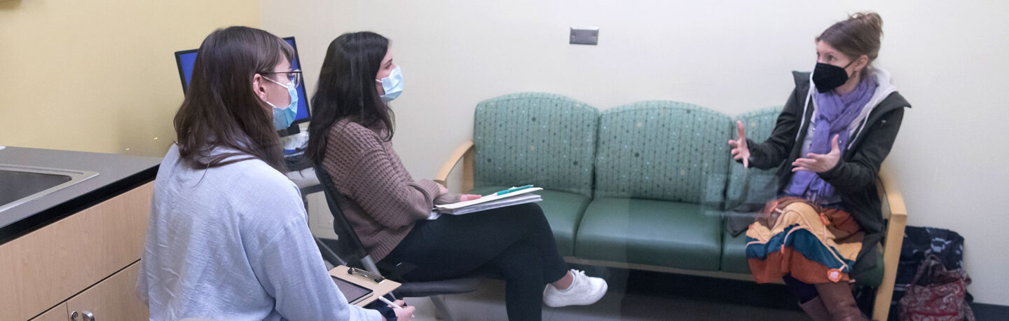 Students conducting a practice counseling session in an observation room