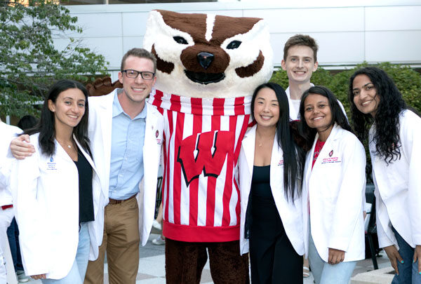 Students in their white coats pose with Bucky Badger