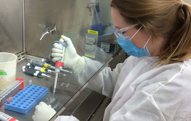 A woman wearing PPE working in a lab