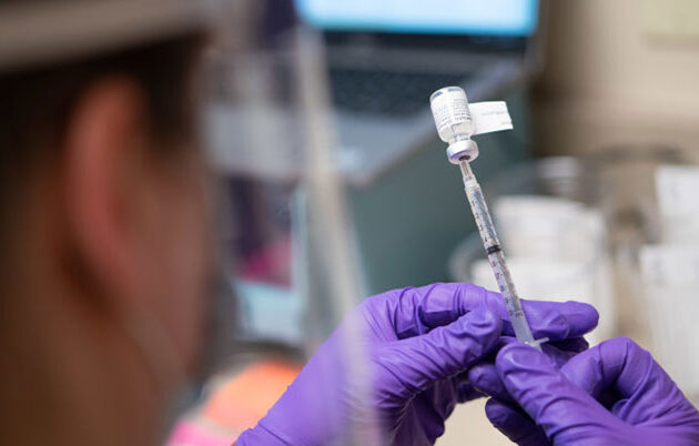 A health professional pulling a vaccine into a syringe