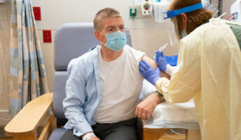 A masked professional receiving a vaccine