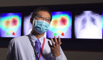 A professional speaks next to x-rays of the lungs and chest