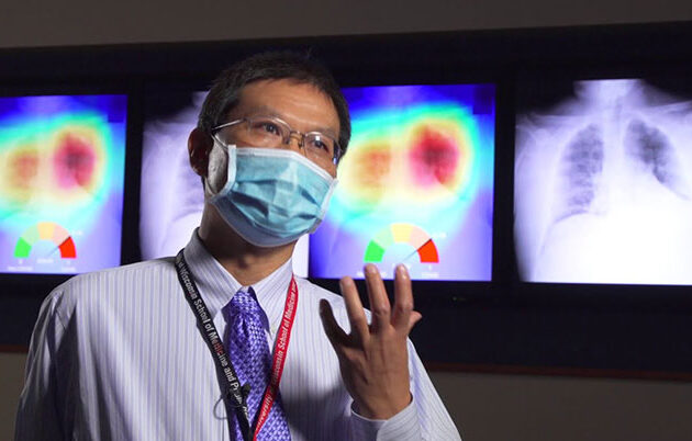 A professional speaks next to x-rays of the lungs and chest
