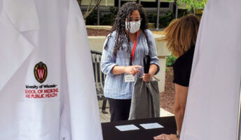 A masked student picking up their new white coat