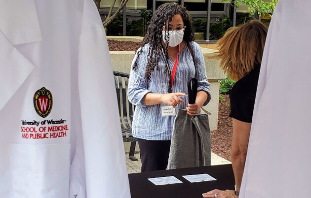 A masked student picking up their new white coat