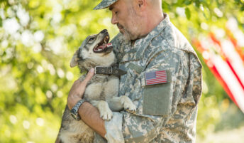 A military veteran holding a happy puppy