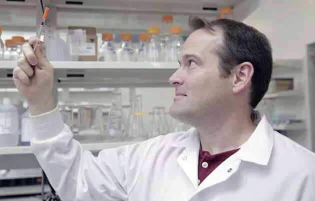 A researcher in a lab inspecting liquid in a syringe
