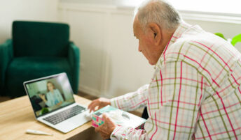 An elderly man using a laptop during a virtual doctor visit