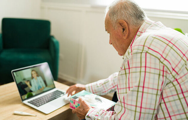 An elderly man using a laptop during a virtual doctor visit